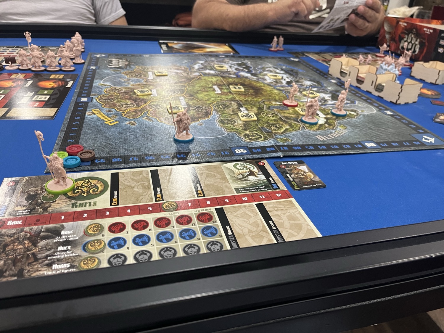 A four-player Blood Rage game in progress, with clan miniatures contesting provinces around the Yggdrasil board and a monster figure on the map