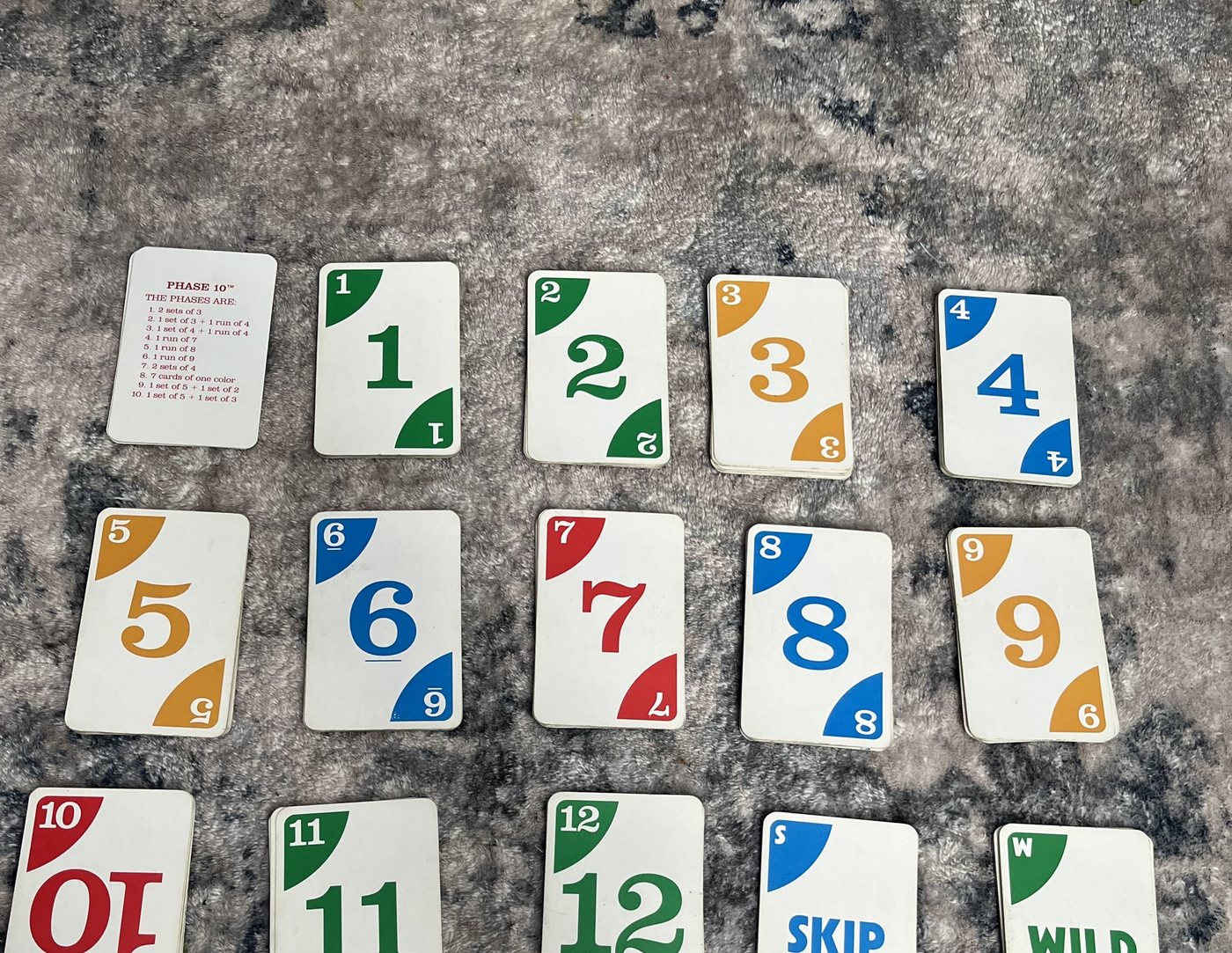 Phase 10 cards numbered 1 to 12, a Skip, a Wild and a phase reference card