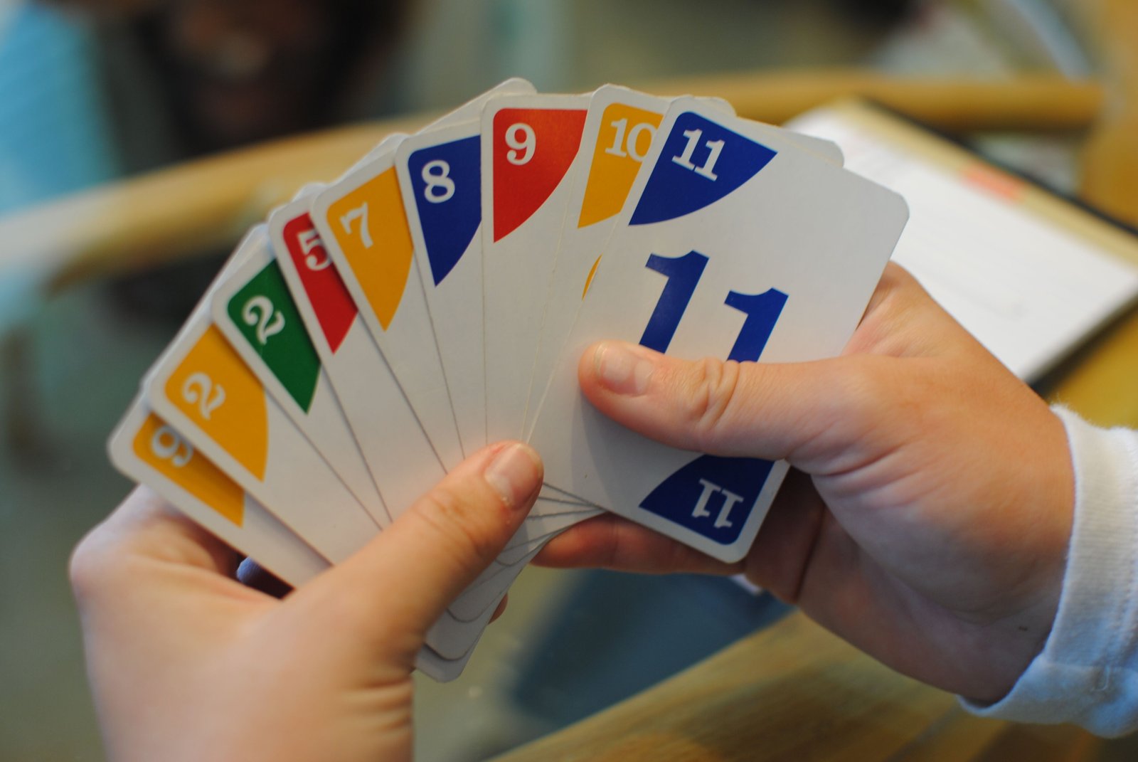 A hand of Phase 10 cards fanned out, showing numbers in four colors