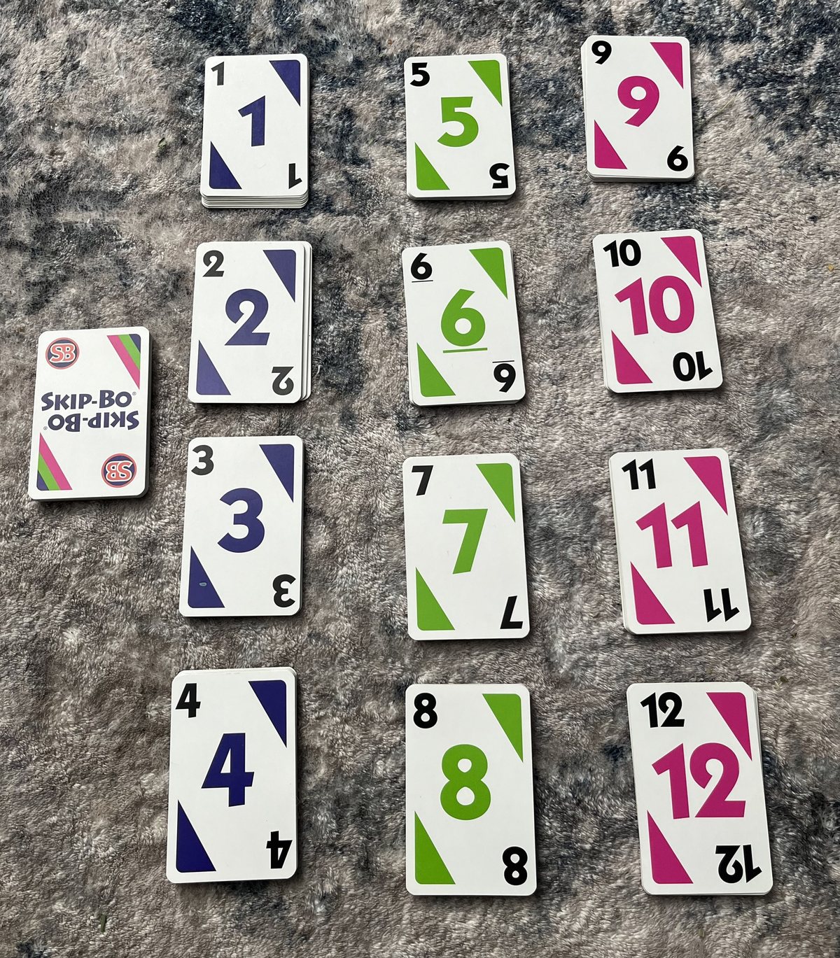 Skip-Bo number cards 1 through 12 laid out in three columns next to a Skip-Bo wild card