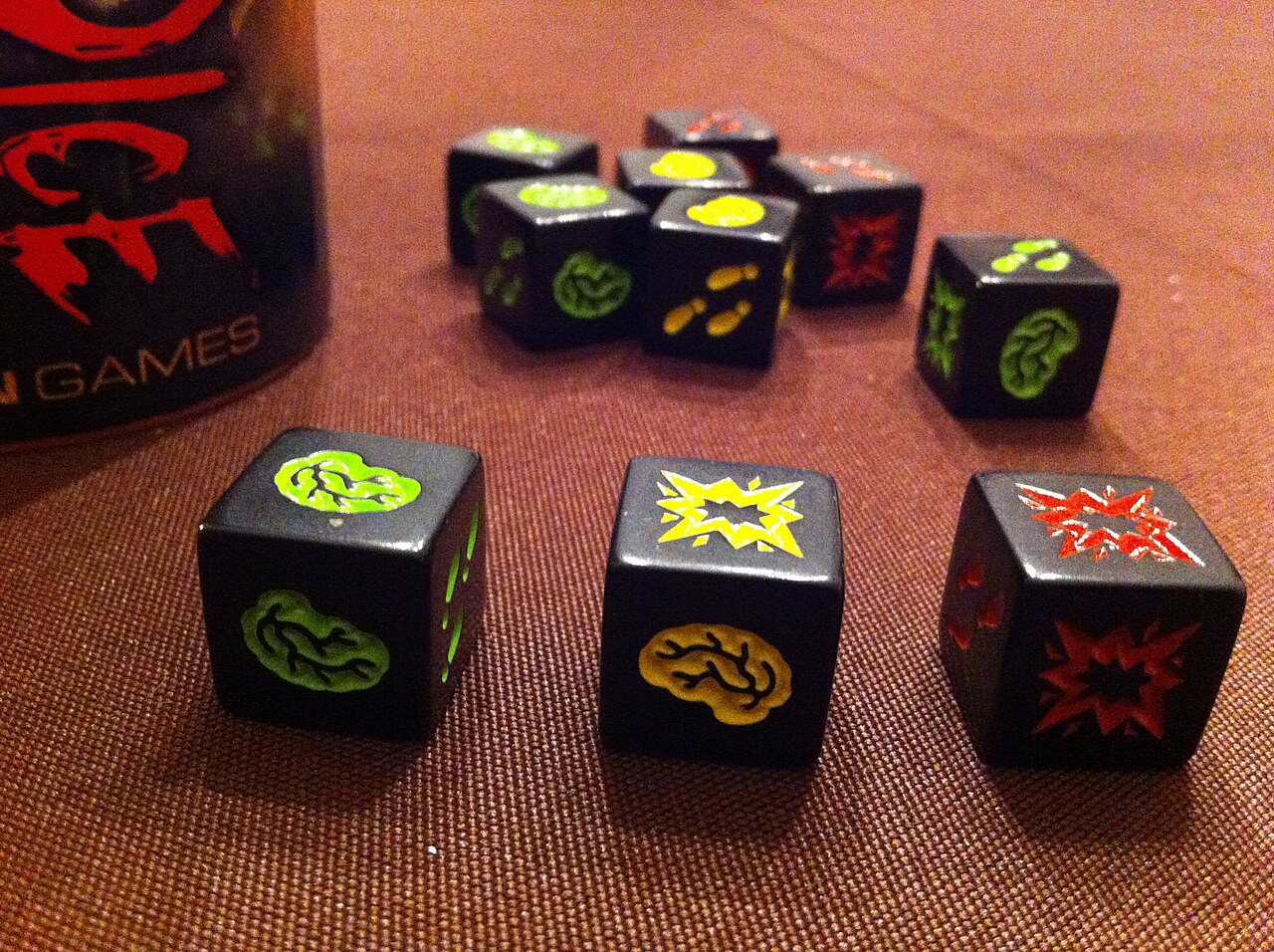 Zombie Dice showing green, yellow and red dice with brain, shotgun and footstep faces